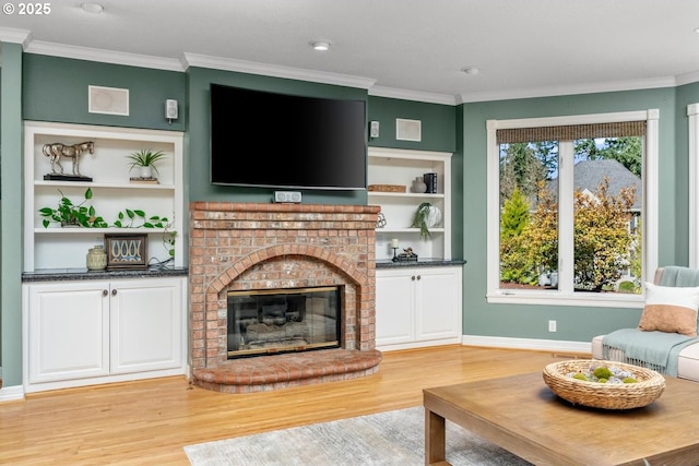 living room featuring built in shelves, light wood-style flooring, a fireplace, and ornamental molding