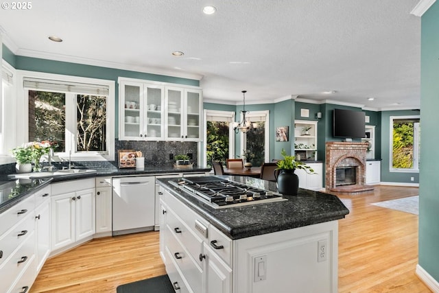 kitchen featuring dishwashing machine, a kitchen island, stainless steel gas cooktop, a sink, and light wood-type flooring