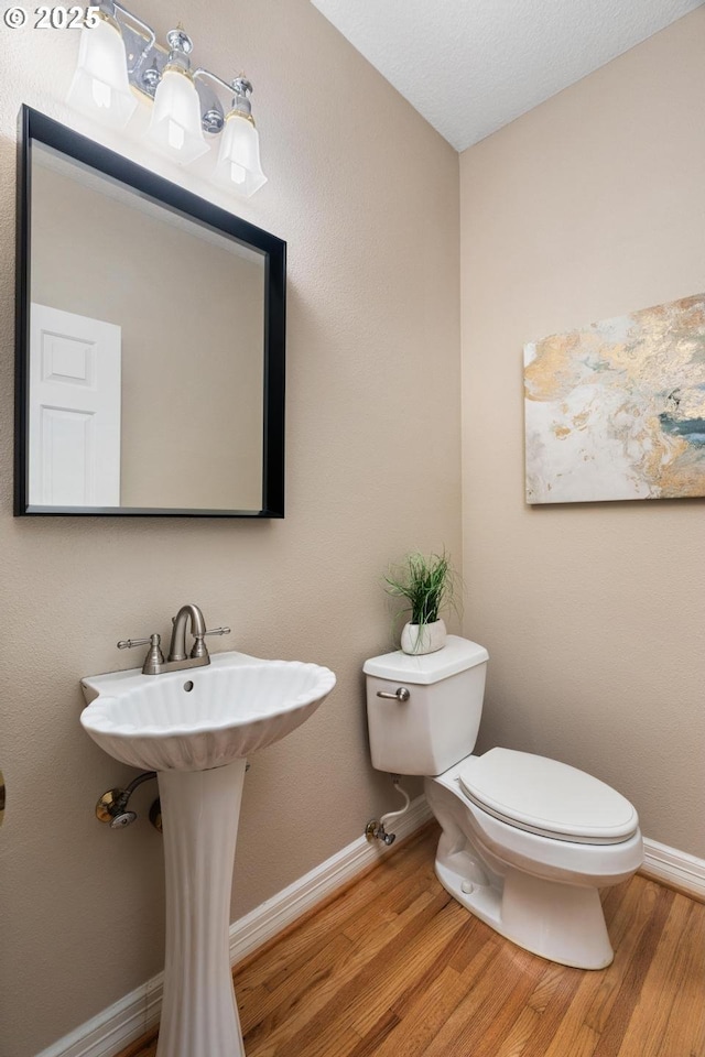 bathroom featuring toilet, wood finished floors, and baseboards
