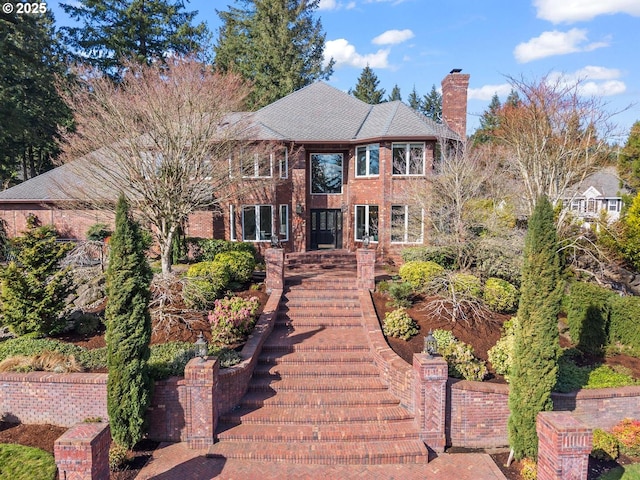 view of front of home featuring brick siding and a chimney
