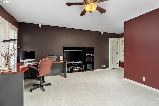 carpeted office space featuring a ceiling fan and baseboards