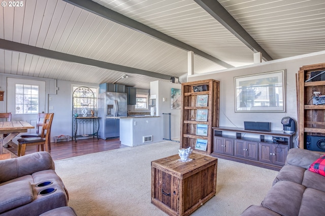 living area with vaulted ceiling with beams, light colored carpet, and visible vents