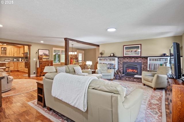 5583 54th Ct, Salem, OR 97317 - living room with light wood-type flooring, recessed lighting, baseboards, a brick fireplace, and a chandelier
