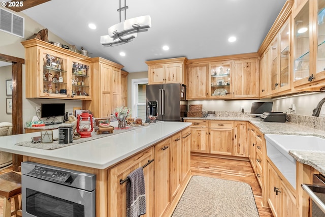 kitchen featuring light brown cabinets, sink, hanging light fixtures, appliances with stainless steel finishes, and light hardwood / wood-style floors