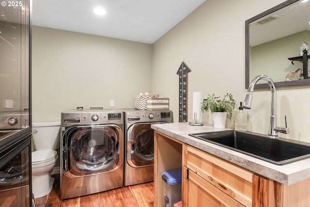 washroom with washing machine and dryer, sink, and light wood-type flooring