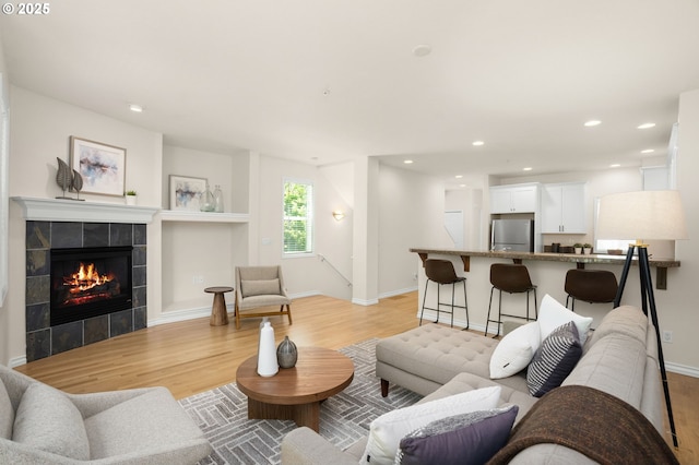 10494 NW Forestview Way, Portland, OR 97229 - living room featuring light wood-style floors, a tile fireplace, baseboards, and recessed lighting