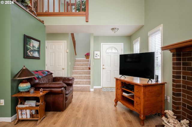 living room featuring light wood finished floors, stairway, a towering ceiling, and baseboards