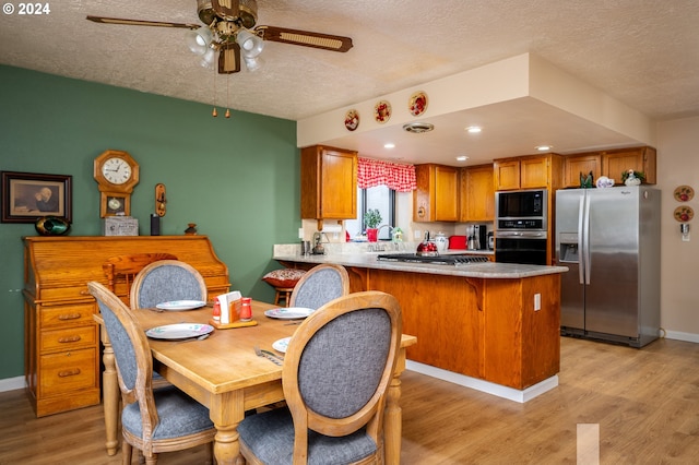 kitchen with a peninsula, appliances with stainless steel finishes, brown cabinetry, and light wood-style flooring