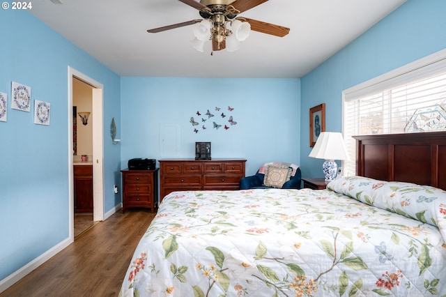 bedroom featuring ensuite bath, baseboards, ceiling fan, and wood finished floors