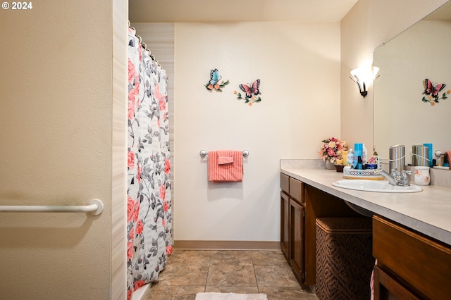 bathroom featuring stone finish flooring, a shower with shower curtain, vanity, and baseboards