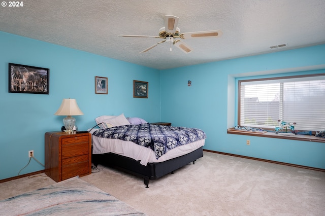 carpeted bedroom with a textured ceiling, a ceiling fan, visible vents, and baseboards