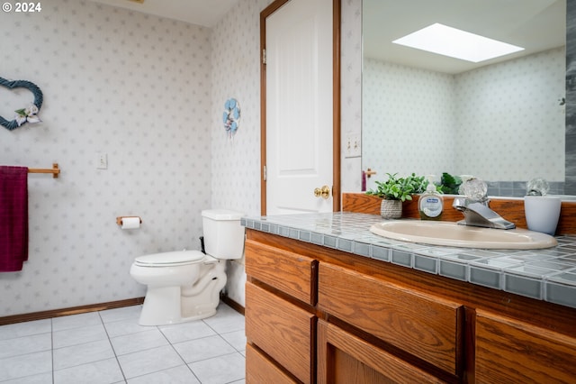 bathroom featuring a skylight, wallpapered walls, toilet, baseboards, and tile patterned floors