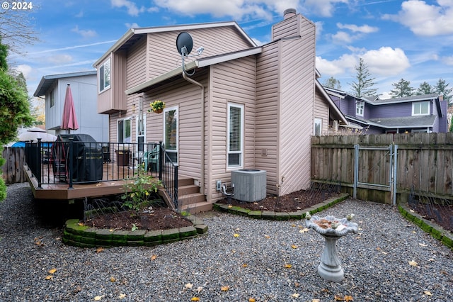 back of property featuring a deck, central AC unit, a chimney, and fence