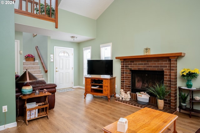 living area featuring baseboards, stairway, wood finished floors, a fireplace, and high vaulted ceiling