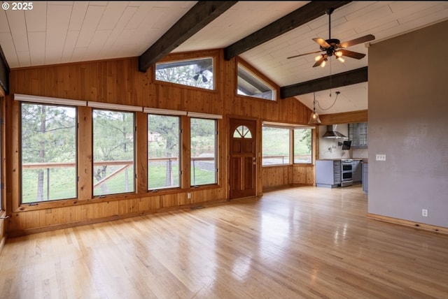 unfurnished living room with wood finished floors, wooden walls, a ceiling fan, and baseboards
