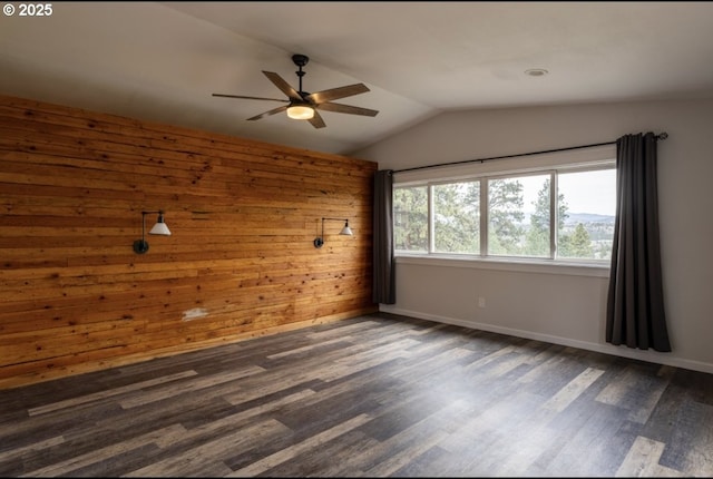 unfurnished room with a ceiling fan, dark wood-style flooring, lofted ceiling, wooden walls, and baseboards