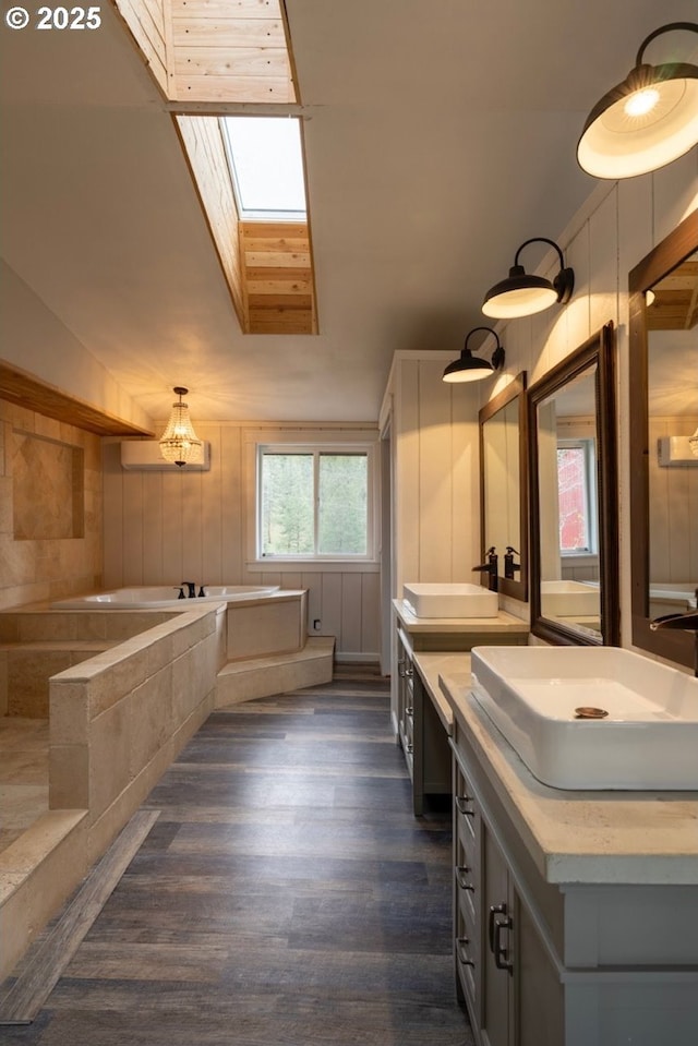full bathroom featuring a skylight, a garden tub, wood finished floors, double vanity, and lofted ceiling
