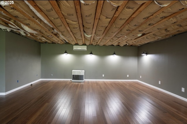 below grade area with a wall unit AC, baseboards, and wood finished floors