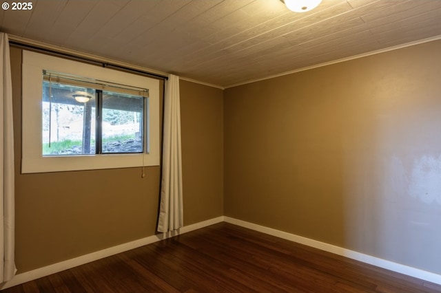 spare room featuring dark wood finished floors, baseboards, and ornamental molding