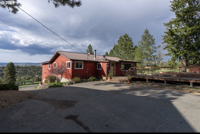 view of front of property featuring a deck, metal roof, and asphalt driveway