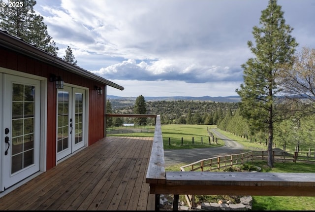 wooden terrace with french doors, a mountain view, and a rural view
