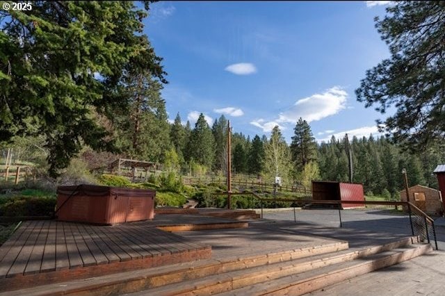 view of home's community featuring a wooden deck, a jacuzzi, and a view of trees