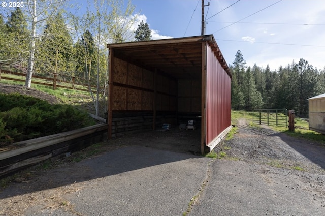 view of pole building with fence and asphalt driveway