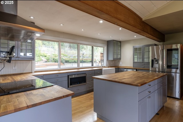 kitchen with wood counters, appliances with stainless steel finishes, gray cabinets, island range hood, and light wood-style floors