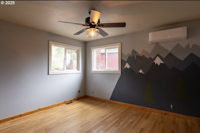 unfurnished room with baseboards, a wall unit AC, ceiling fan, and wood finished floors