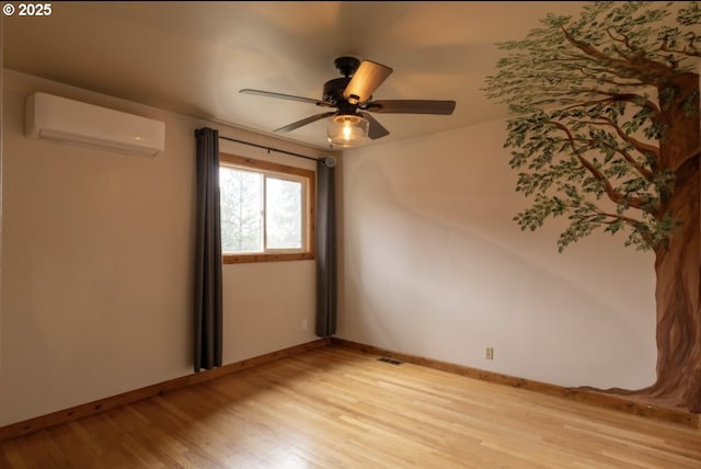 unfurnished room with a wall mounted air conditioner, light wood finished floors, a ceiling fan, and baseboards