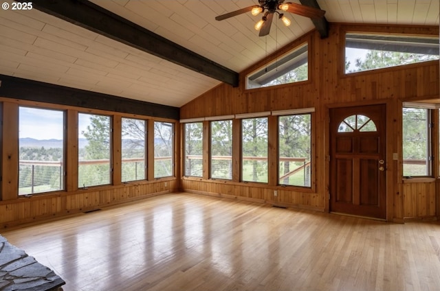 unfurnished sunroom featuring wooden walls, wood finished floors, and a mountain view