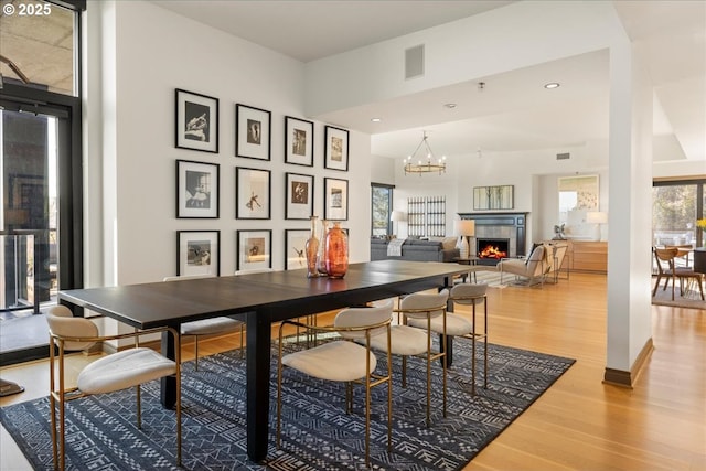 dining space with an inviting chandelier, hardwood / wood-style floors, and a fireplace