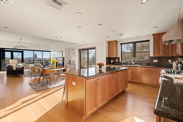 kitchen with dark stone counters, sink, a kitchen island, and light hardwood / wood-style flooring