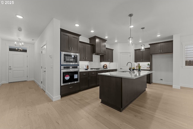15129 SW Huntwood St, Tigard, OR 97224 - kitchen with stainless steel appliances, light wood-style flooring, baseboards, tasteful backsplash, and a sink