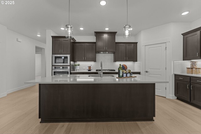 15129 SW Huntwood St, Tigard, OR 97224 - kitchen with appliances with stainless steel finishes, a sink, light wood-style flooring, light countertops, and backsplash
