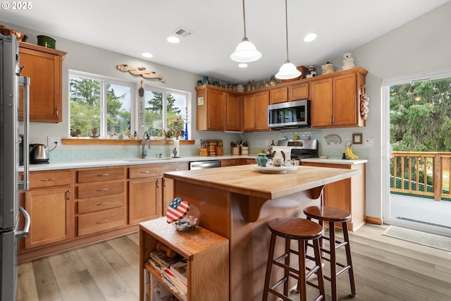 1395 Dooley Ln, Gearhart, OR 97138 - kitchen with appliances with stainless steel finishes, butcher block counters, light wood finished floors, a breakfast bar, and decorative light fixtures