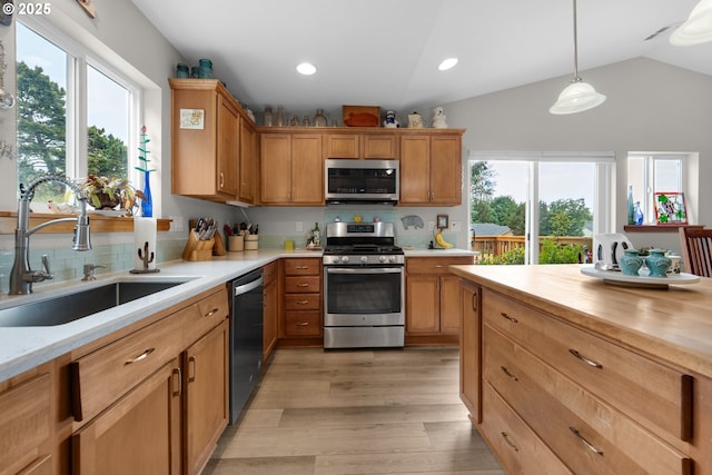 1395 Dooley Ln, Gearhart, OR 97138 - kitchen featuring appliances with stainless steel finishes, light wood-type flooring, vaulted ceiling, tasteful backsplash, and hanging light fixtures