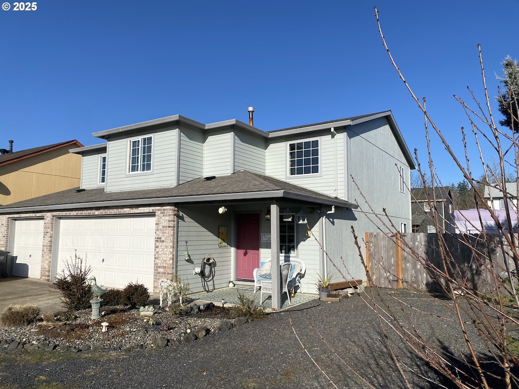 view of front facade featuring an attached garage, brick siding, fence, and roof with shingles