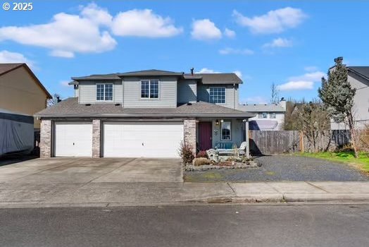 traditional-style home with concrete driveway, an attached garage, and fence