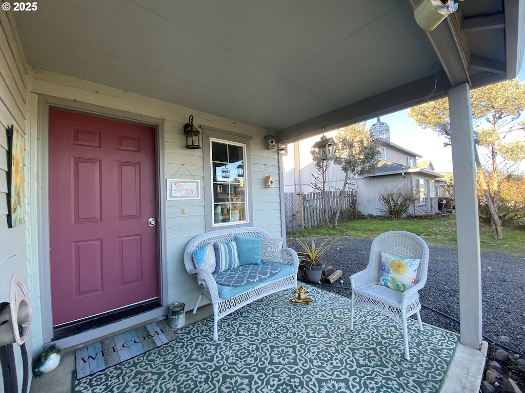 view of exterior entry with covered porch and fence