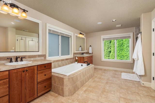 8967 SW 184th Dr, Beaverton, OR 97007 - bathroom featuring two vanities, a bath, tile patterned flooring, a textured ceiling, and recessed lighting