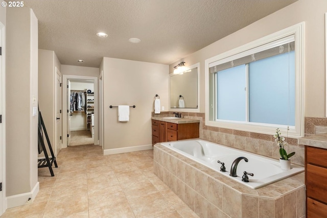 8967 SW 184th Dr, Beaverton, OR 97007 - bathroom with vanity, a bath, a textured ceiling, a spacious closet, and recessed lighting
