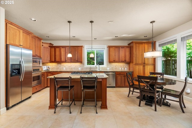 8967 SW 184th Dr, Beaverton, OR 97007 - kitchen featuring appliances with stainless steel finishes, brown cabinets, plenty of natural light, tasteful backsplash, and recessed lighting