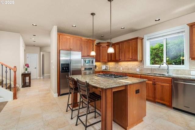 8967 SW 184th Dr, Beaverton, OR 97007 - kitchen featuring appliances with stainless steel finishes, tasteful backsplash, a center island, brown cabinets, and light stone countertops