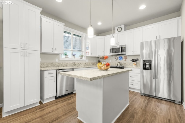 kitchen featuring white cabinetry, hanging light fixtures, stainless steel appliances, a kitchen island, and dark hardwood / wood-style flooring