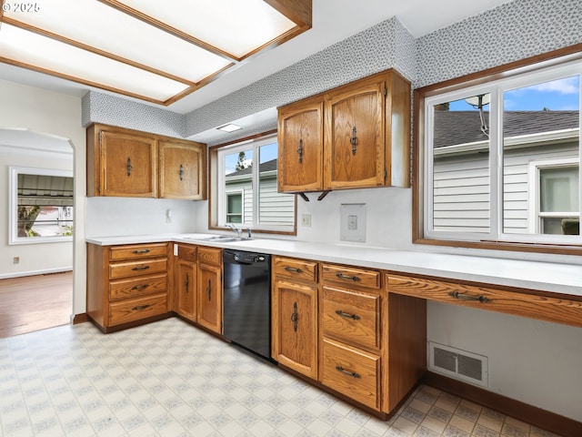 kitchen featuring light countertops, brown cabinetry, black dishwasher, light floors, and visible vents