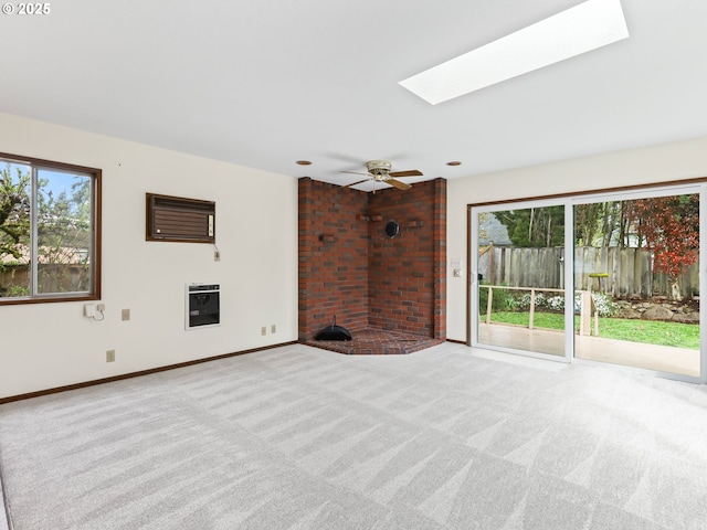 unfurnished living room with a skylight, baseboards, carpet, and a ceiling fan