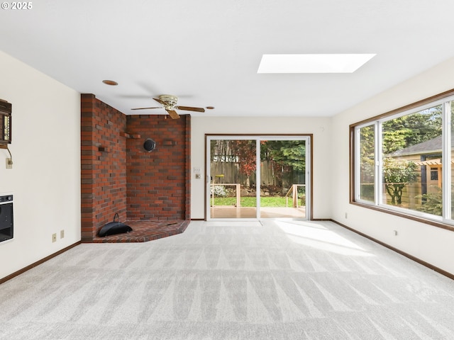 interior space featuring baseboards, a ceiling fan, and a skylight