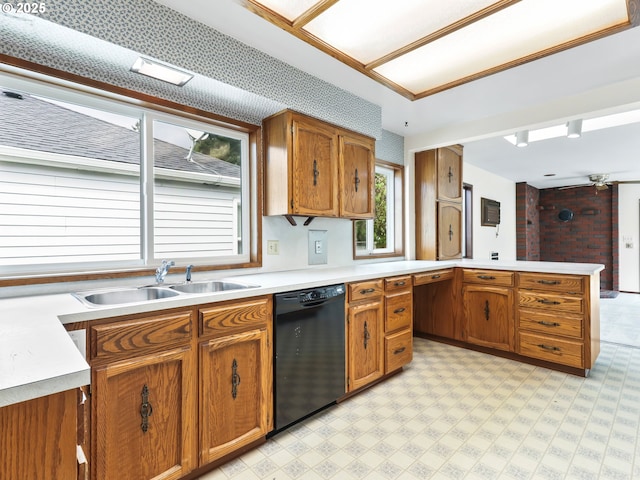 kitchen with brown cabinets, a sink, light countertops, a peninsula, and black dishwasher
