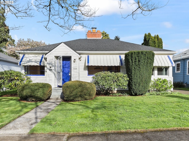 bungalow-style house with a front lawn, roof with shingles, and a chimney